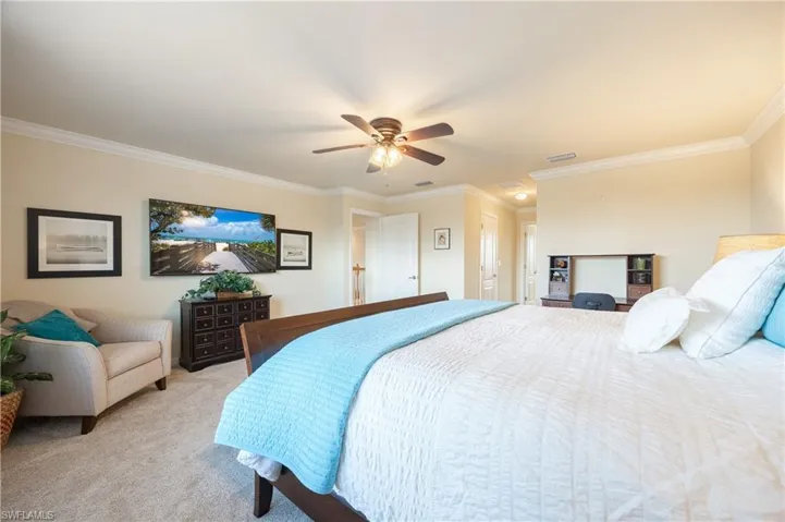 Bedroom featuring ceiling fan, light colored carpet, and ornamental molding