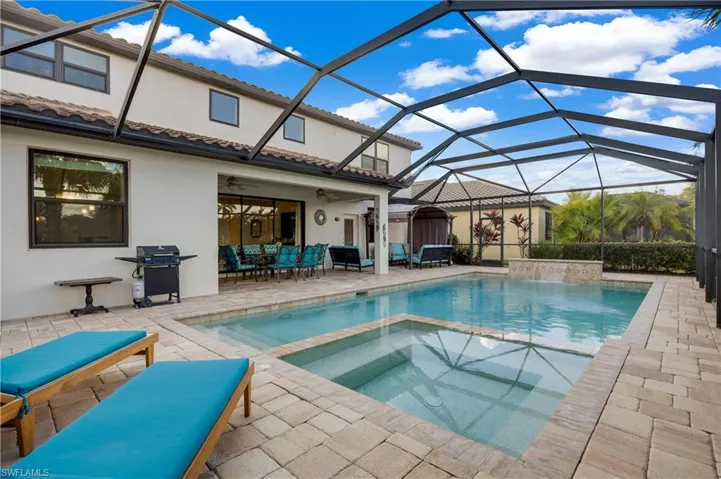 View of pool with an in ground hot tub, ceiling fan, a lanai, and a grill