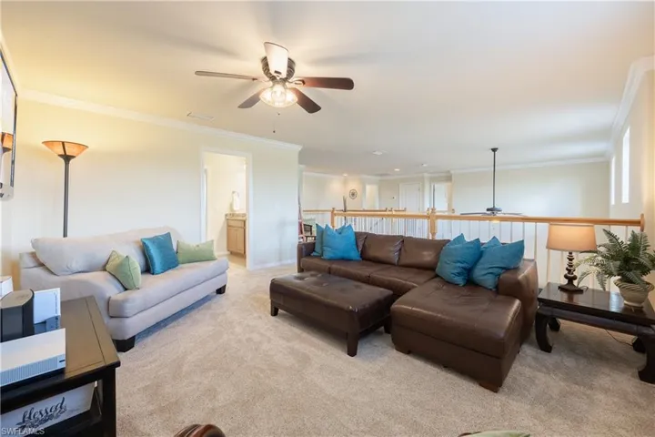 Living room featuring crown molding, ceiling fan, and light colored carpet
