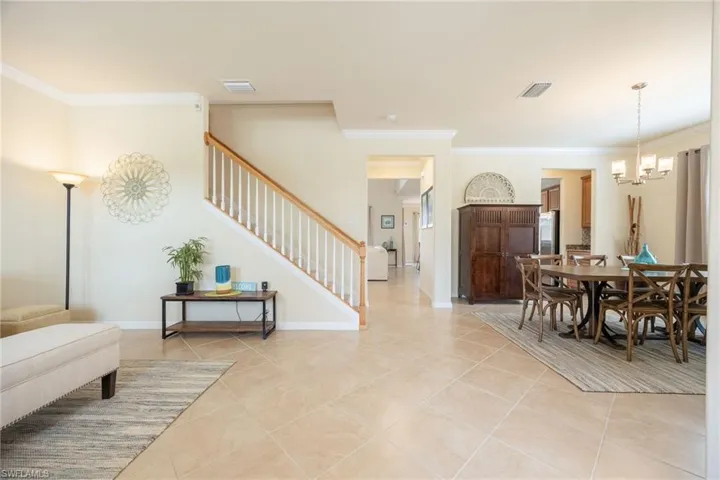 Dining area featuring light tile patterned floors, crown molding, and an inviting chandelier