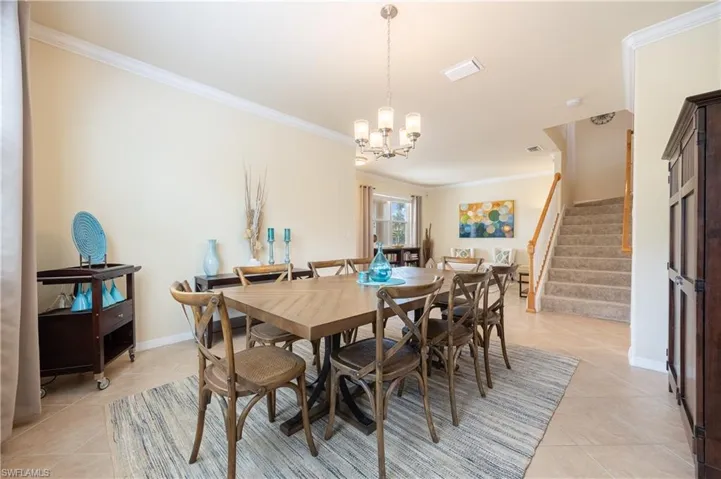 Dining area featuring light tile patterned flooring, crown molding, and a chandelier