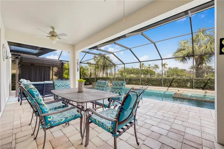 View of patio featuring glass enclosure, ceiling fan, and an outdoor hangout area