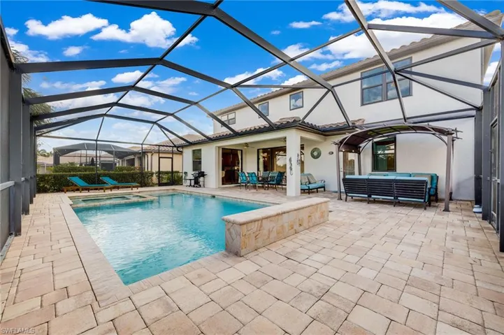 View of swimming pool featuring glass enclosure, ceiling fan, a patio area, and an outdoor hangout area