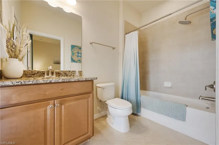 Full bathroom with tile patterned flooring, vanity, shower / tub combo, and toilet
