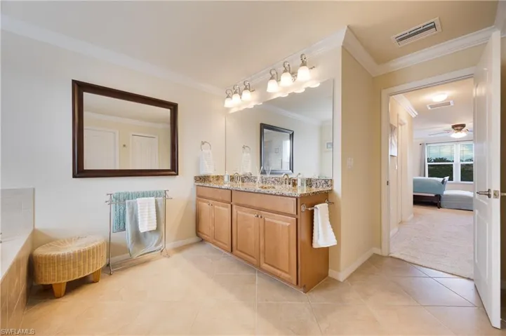 Bathroom with tile patterned flooring, vanity, ceiling fan, and ornamental molding