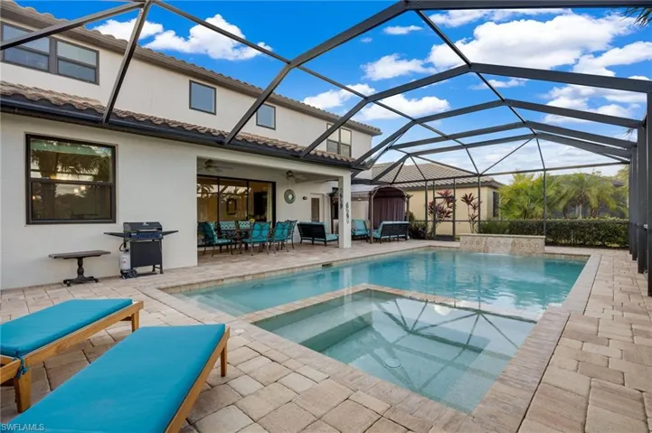 View of swimming pool with area for grilling, glass enclosure, ceiling fan, and a patio