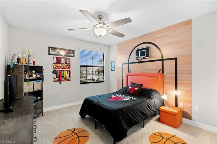 Bedroom with ceiling fan, wood walls, and light carpet