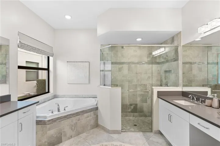 Bathroom featuring vanity, tile patterned floors, and plus walk in shower