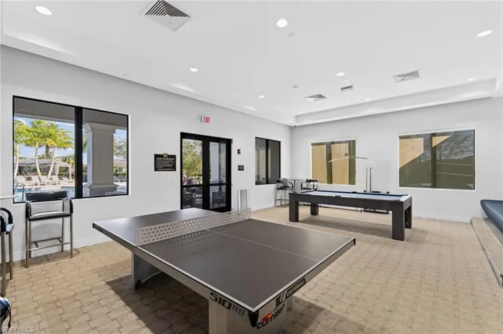 Gym with a tray ceiling, ceiling fan, and light colored carpet