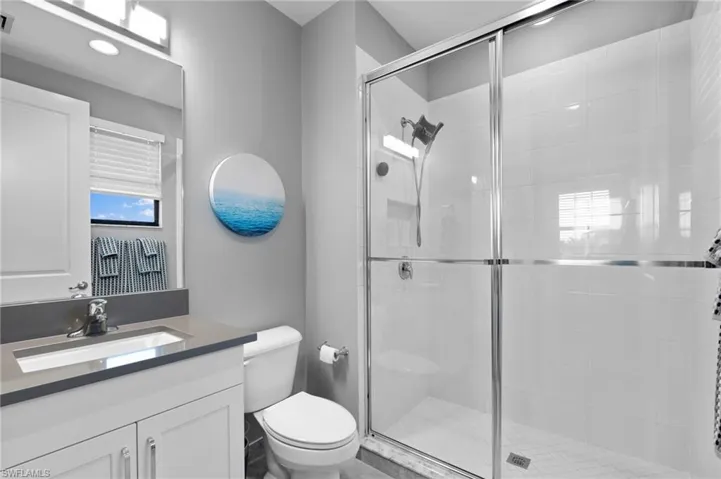 Bathroom featuring walk in shower, toilet, and vanity