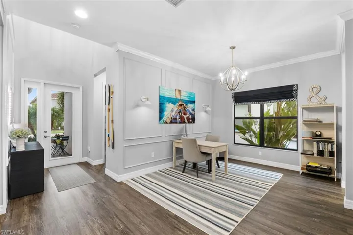 Dining room with ornamental molding, plenty of natural light, a notable chandelier, and dark hardwood / wood-style flooring