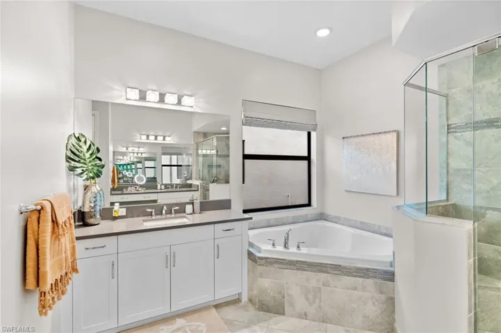 Bathroom with vanity, tile patterned flooring, and shower with separate bathtub
