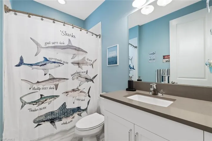 Bathroom featuring a shower with curtain, toilet, and vanity