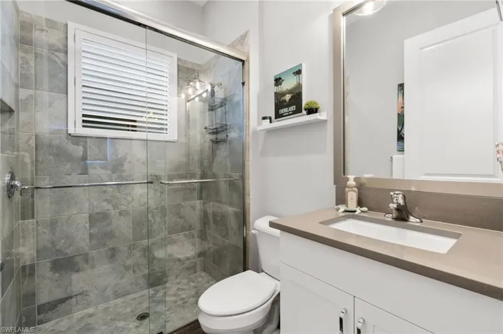 Bathroom featuring vanity, toilet, and a shower with shower door