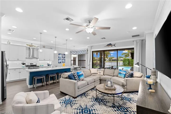 Living room with light wood-type flooring, ceiling fan, sink, and ornamental molding