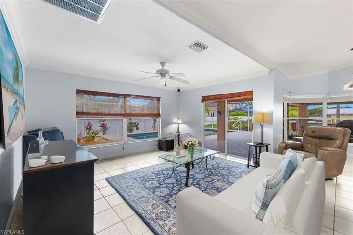 Living room with ceiling fan, crown molding, and light tile floors