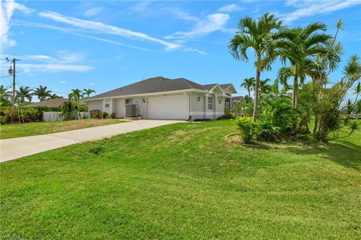 Ranch-style home featuring a garage and a front lawn
