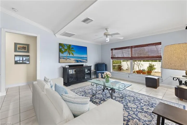 Living room with vaulted ceiling, ornamental molding, and ceiling fan