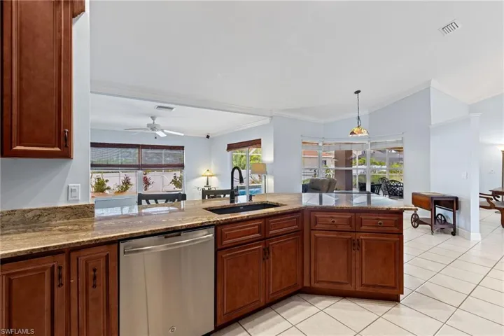 Kitchen with sink, stone counters, dishwasher, and ceiling fan
