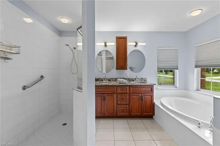 Bathroom with double vanity, tile flooring, and independent shower and bath