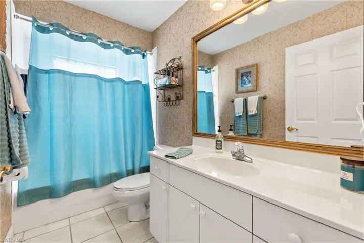 Full bathroom featuring tile flooring, shower / tub combo with curtain, vanity, and toilet