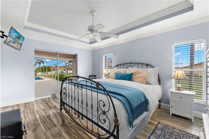 Bedroom featuring access to outside, a tray ceiling, and multiple windows