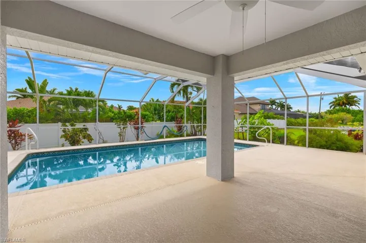 View of swimming pool with a patio, ceiling fan, and glass enclosure