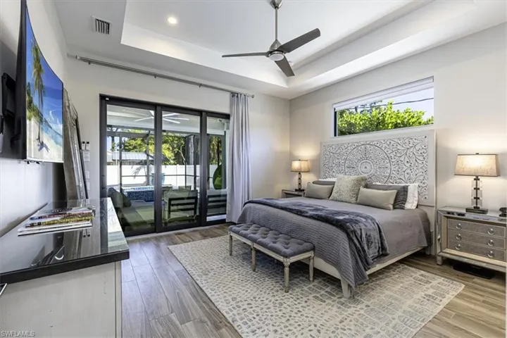 Bedroom featuring access to outside, multiple windows, a ceiling fan, and wood finished floors
