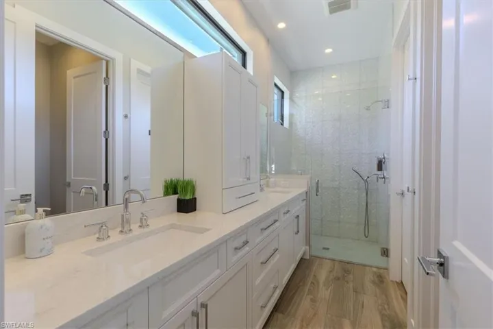 Bathroom featuring double vanity, a stall shower, light wood finished floors, and recessed lighting