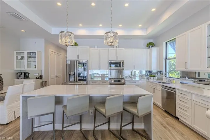 Kitchen featuring glass insert cabinets, a tray ceiling, white cabinetry, a kitchen breakfast bar, and a kitchen island
