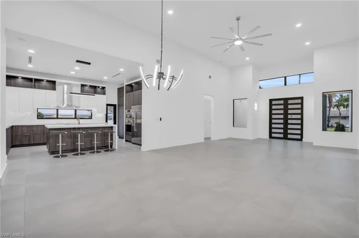 Tiled living room featuring a towering ceiling, ceiling fan with notable chandelier