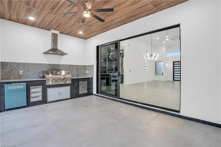 Kitchen featuring wall chimney range hood, tasteful backsplash, wood ceiling, and ceiling fan with notable chandelier