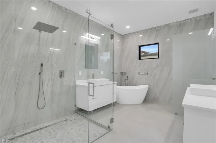 Bathroom with independent shower and bath, tile walls, and frosted glass privacy wall