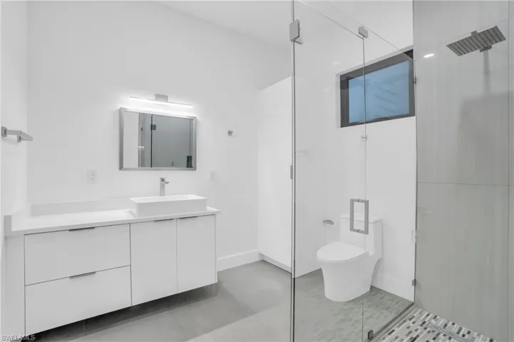 Bathroom featuring tile floors, a shower with shower door, vanity, and toilet