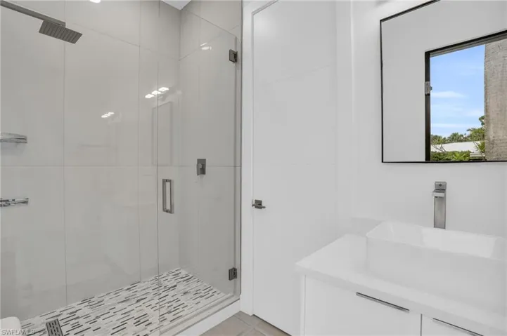 Bathroom with sink, an enclosed shower, and tile flooring