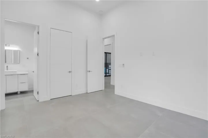 Unfurnished bedroom with ensuite bathroom and light tile floors