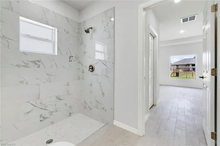 Bathroom with tiled shower and hardwood / wood-style floors