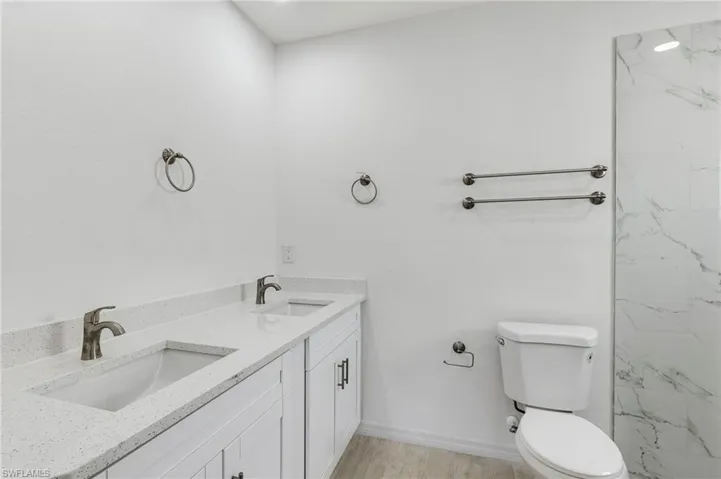 Bathroom featuring toilet, double sink vanity, and wood-type flooring