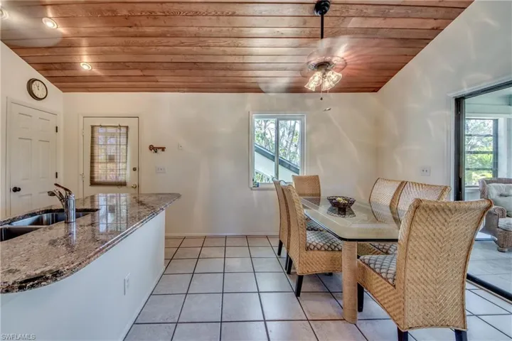 Tiled dining space featuring vaulted ceiling, sink, wood ceiling, and a healthy amount of sunlight