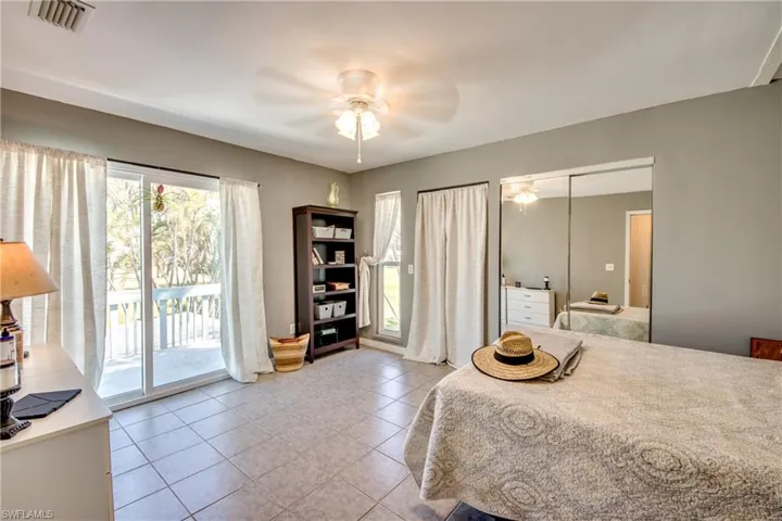 Tiled bedroom featuring multiple windows, a closet, access to outside, and ceiling fan