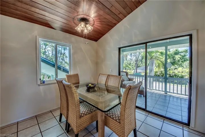 Tiled dining space featuring lofted ceiling, a healthy amount of sunlight, and wood ceiling