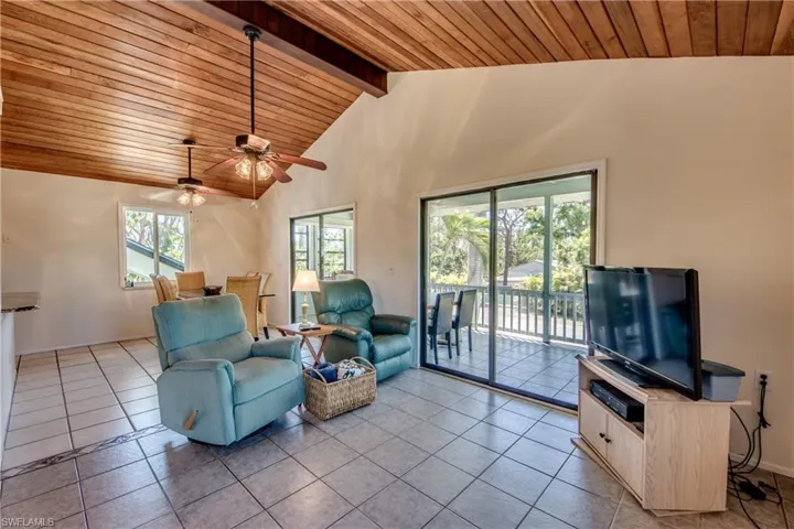 Tiled living room featuring wood ceiling, ceiling fan, a healthy amount of sunlight, and beamed ceiling
