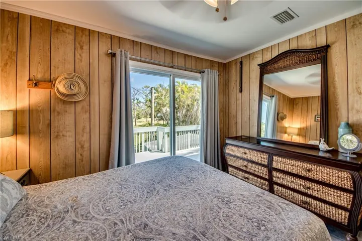Bedroom with ceiling fan, access to outside, ornamental molding, and wooden walls
