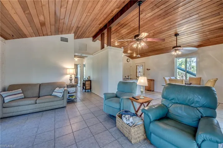 Tiled living room featuring ceiling fan, beam ceiling, high vaulted ceiling, and wooden ceiling