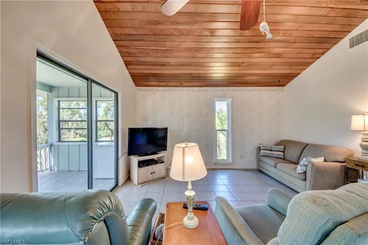 Living room featuring wood ceiling, ceiling fan, vaulted ceiling, and light tile patterned floors