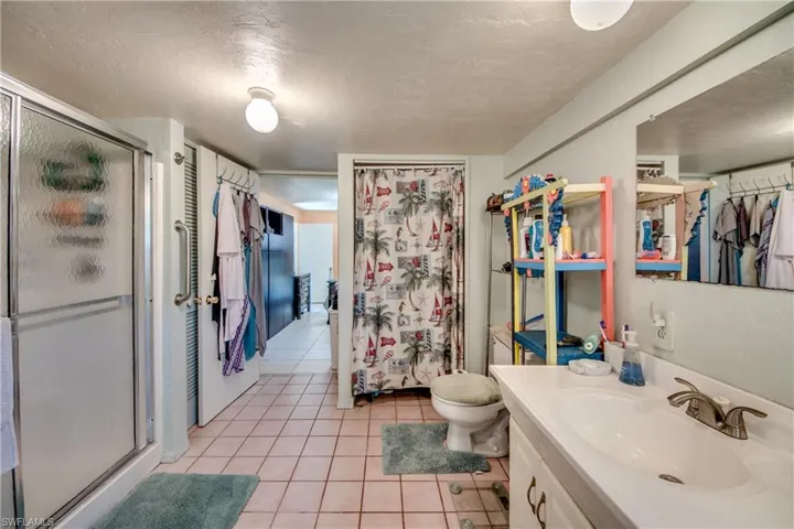 Bathroom with toilet, vanity, tile patterned floors, a textured ceiling, and a shower with shower door