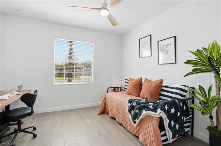 Bedroom featuring light wood-style flooring, ceiling fan, and an office area