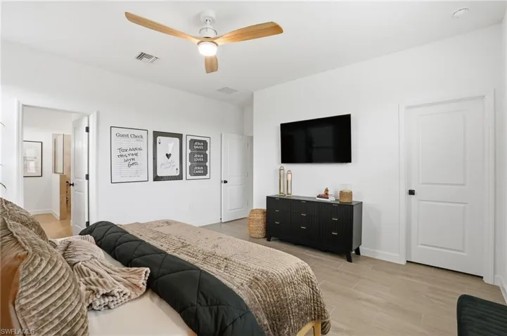 Bedroom with ceiling fan, wood finish floors, and connected bathroom