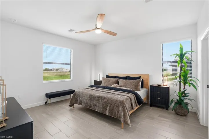 Bedroom featuring wood finish floors, ceiling fan, and multiple windows
