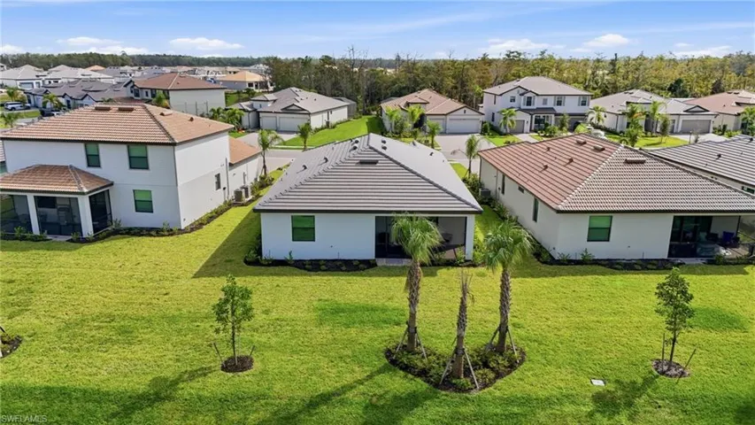 Rear view of property featuring a residential view, stucco siding, and a lawn